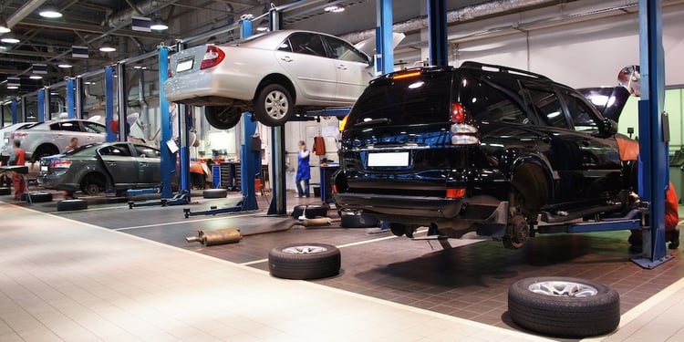 Image showing cars in a clean auto repair shop. Cars are lifted off the ground to be worked on.