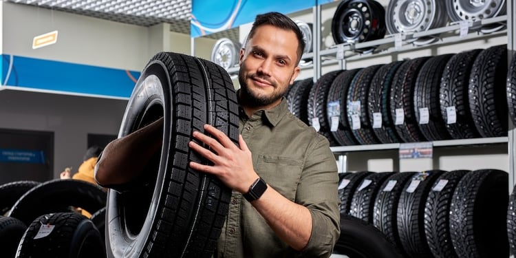 Man in an automotive shop holding a tire