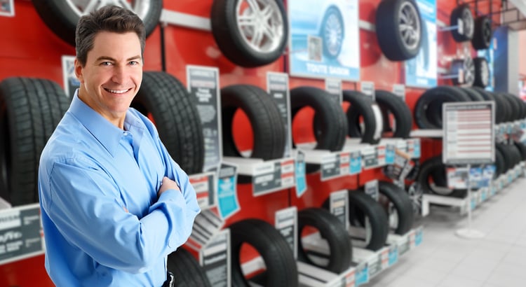 Tire shop owner standing in front of a row of tires